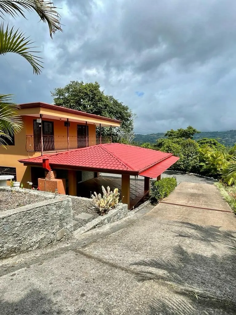 Fachada de la casa con balcón y techo rojo